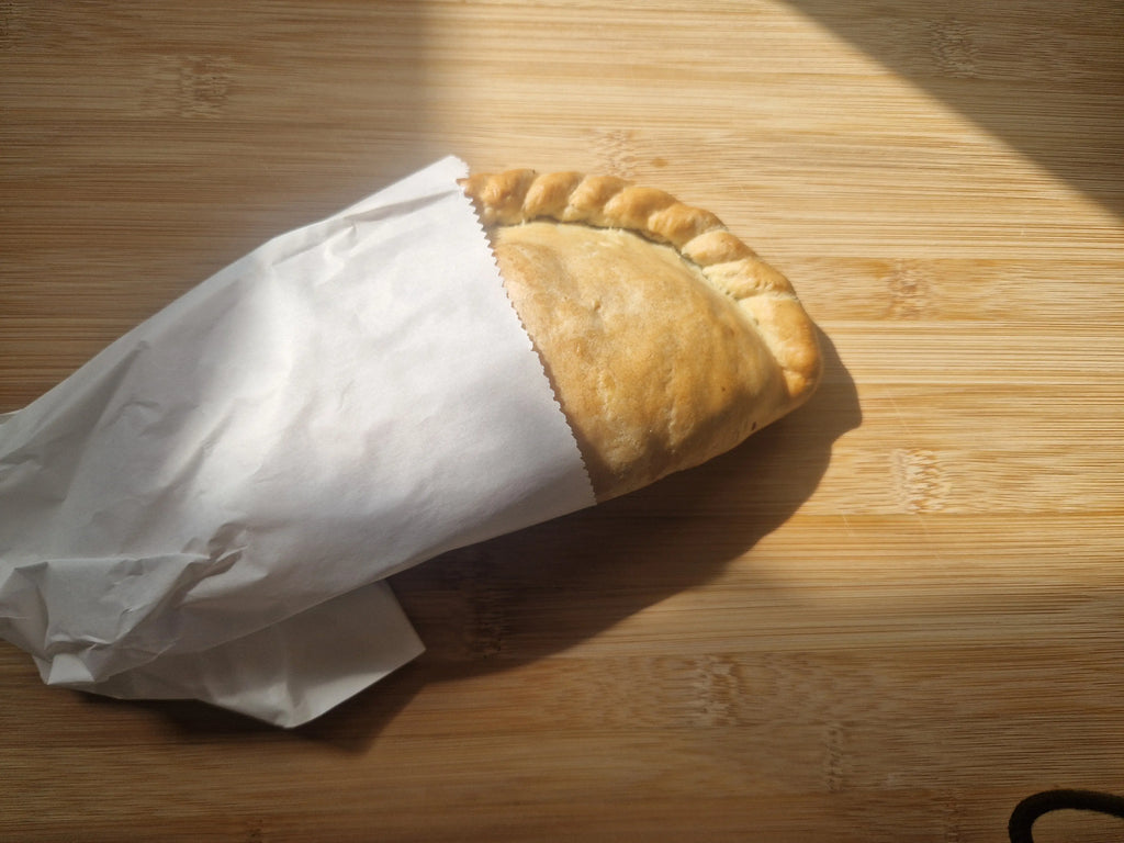 Baked soya mince vegan pasty wrapped in white paper on a wooden surface