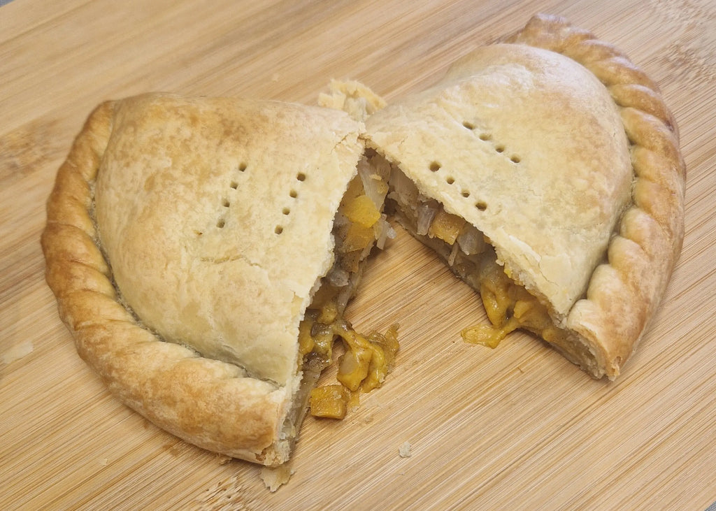 vegan pasty cut in half showing vegan cheese oozing out.