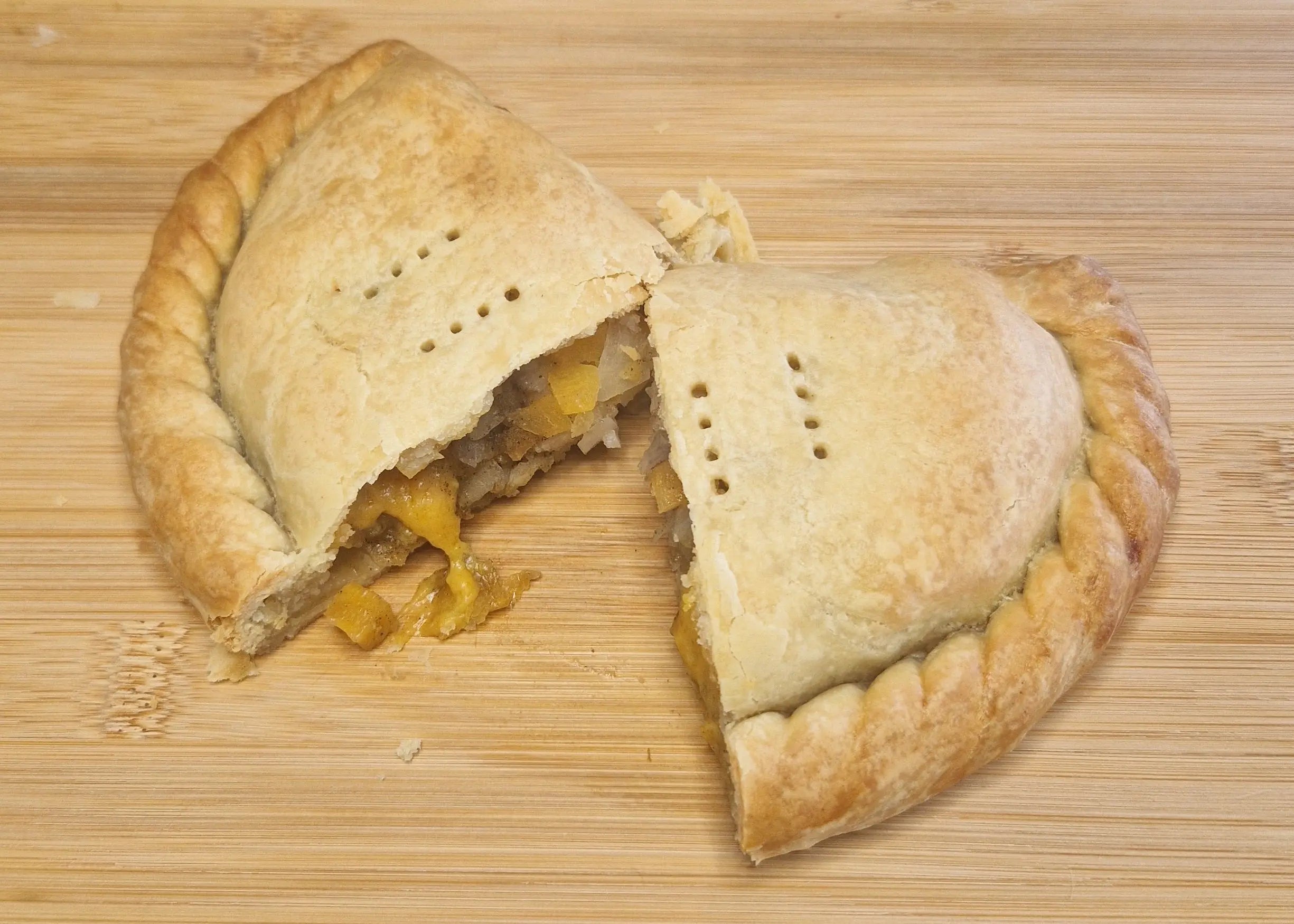 vegan pasty cut in half showing vegan cheese melting inside.